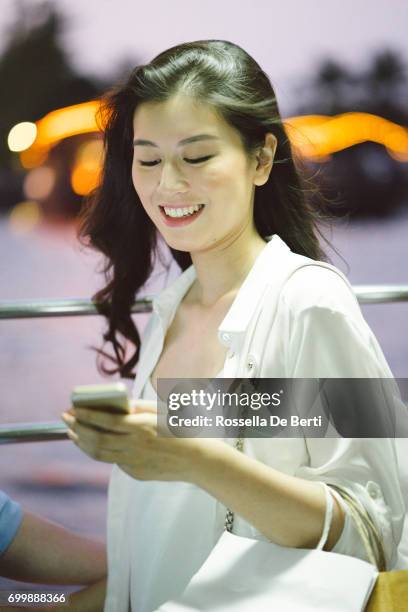 junge frau auf einem kreuzfahrt-schiff in der abenddämmerung mit smartphone - land in sicht stock-fotos und bilder