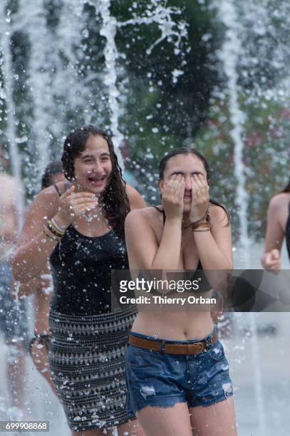 Parisians cooling down in the water of the fountain in the Parc Andre Citroen during the heat wave on June 22, 2017 in Paris, France. France is...