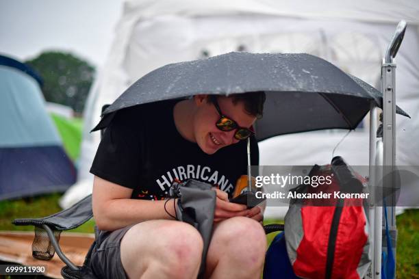 Festival goer seeks shelter from the rain on the camping compound ahead the Hurricane Festival 2017 on June 22, 2017 in Scheessel, Germany. The area...