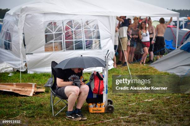 Festival goers seek shelter from the rain on the muddy camping compound ahead the Hurricane Festival 2017 on June 22, 2017 in Scheessel, Germany. The...