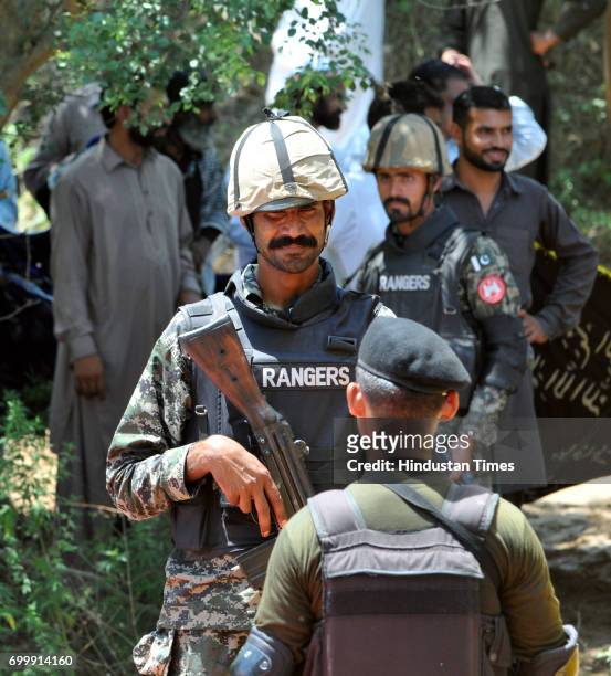 India Border Security Force soldier, back to camera and Pakistani Ranger, face to camera, stand during the ancient shrine of Dalip Singh Baba...