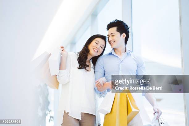 young asian couple enjoying shopping in the mall - couple shopping in shopping mall stock pictures, royalty-free photos & images