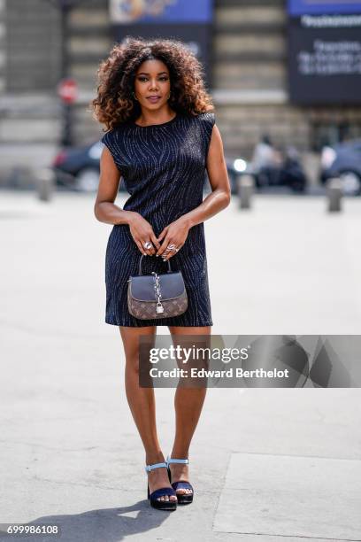 Gabrielle Union wears a black dress, and a Vuitton bag, outside