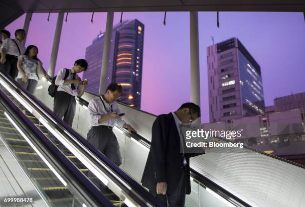 People ride on an escalator near the Bic Camera Akiba electronics store, operated by Bic Camera Inc., from a pedestrian overpass at dusk in the...