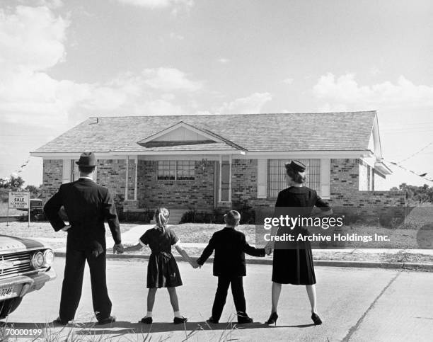 family holding hands, looking at a house for sale (1950) - father son admiration stock pictures, royalty-free photos & images