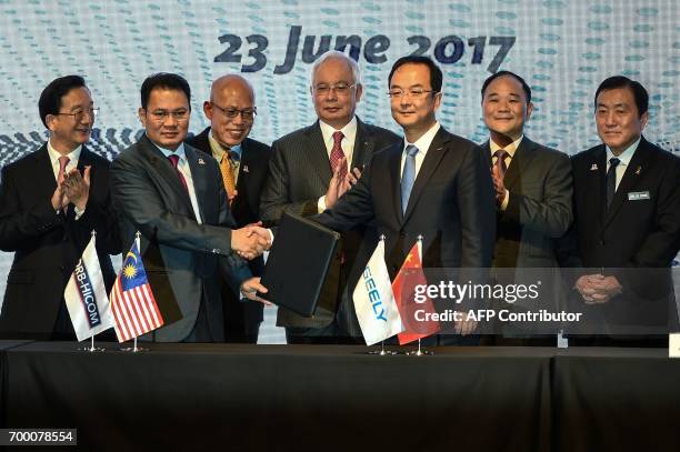 Berhad's Syed Faisal Albar and President of the Zhejiang Geely Holding Group and CEO of Geely Auto Group An Conghui shake hands and exchange...