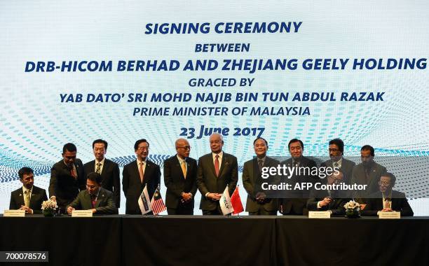 Berhad's Syed Faisal Albar and President of the Zhejiang Geely Holding Group and CEO of Geely Auto Group An Conghui sign documents as Malaysia's...