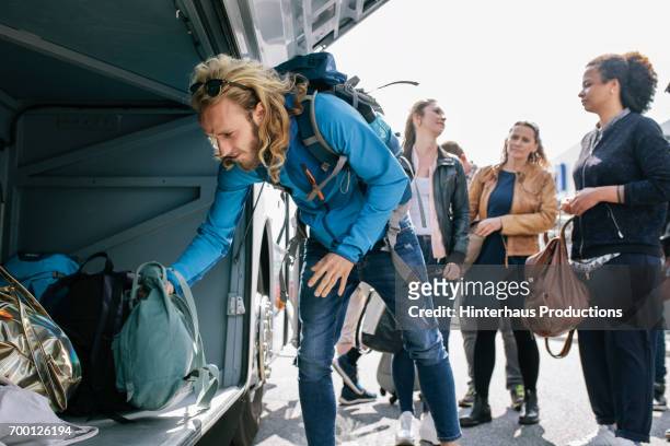a group of young travellers loading a coach with their bags - senior public transportation stock pictures, royalty-free photos & images