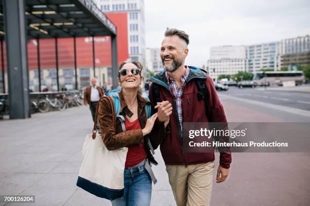 a mature couple hold hands as they walk through berlin - 歩く　カップル ストックフォトと画像