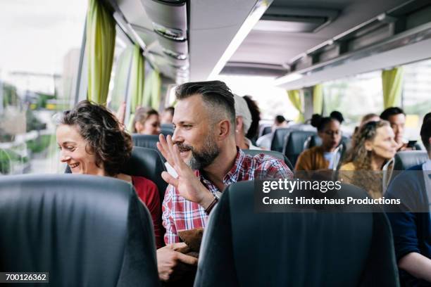 a mature couple sitting on a bus wave goodbye to friends - car photos et images de collection