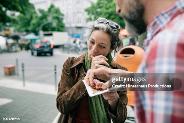 a woman enjoying streetfood with her partner - cuisine de rue photos et images de collection