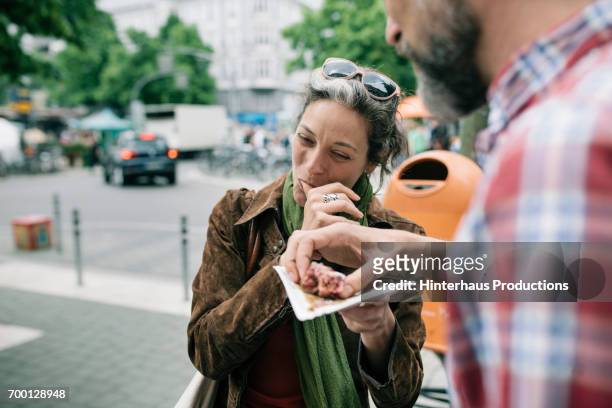 a woman enjoying streetfood with her partner - indulgence stockfoto's en -beelden