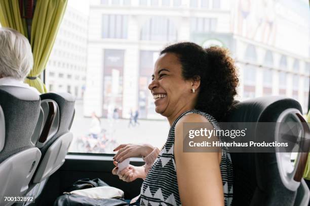 a woman travelling on a bus laughing - bus innen stock-fotos und bilder