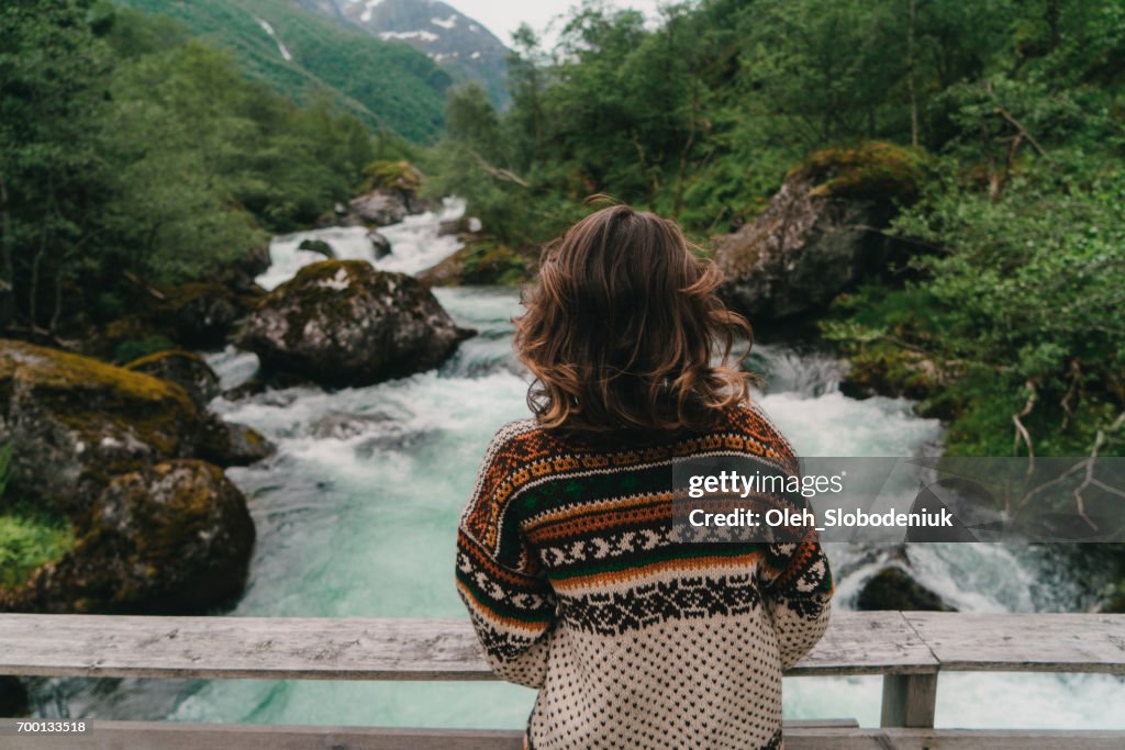 Woman standing on Wooden Bridge on the mountain river in Norway