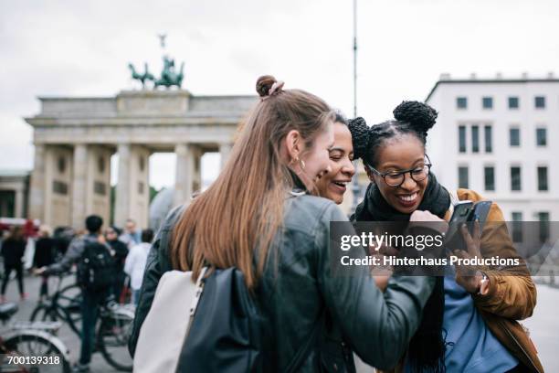 friends looking at a smartphone together - only young women stock pictures, royalty-free photos & images