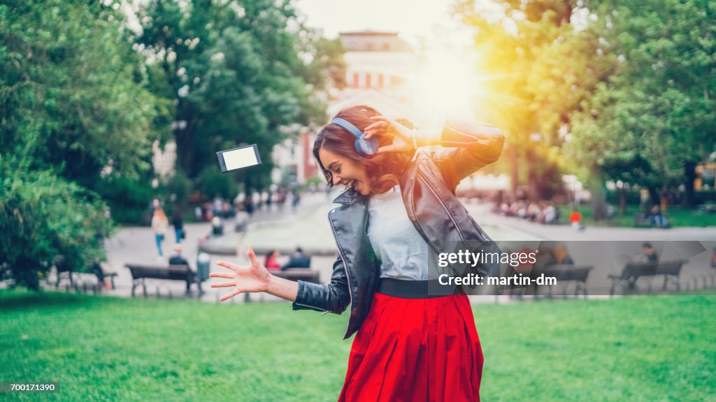 Young girl dancing to the music in the city park