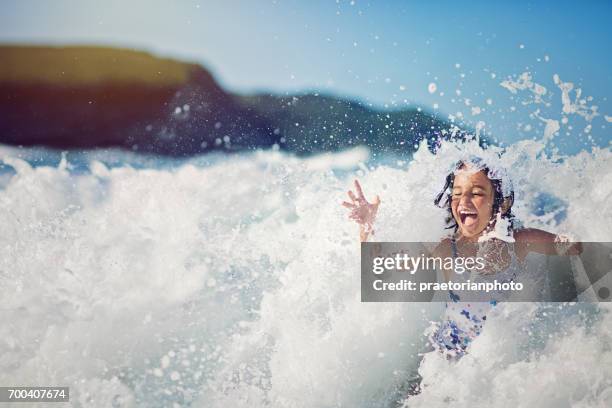 女の子をジャンプして大きな波で、海で遊んで - water glasses ストックフォトと画像