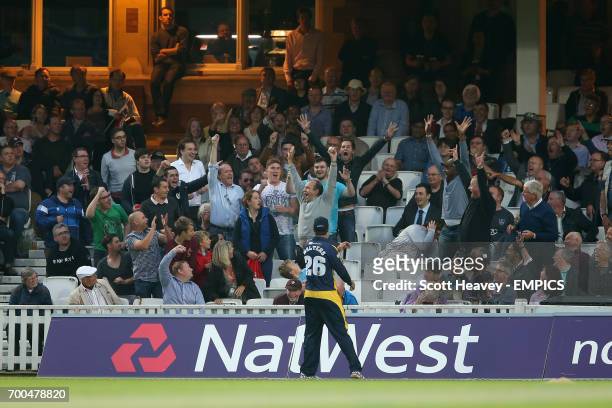 Spectators hold up a cricket ball in the stands