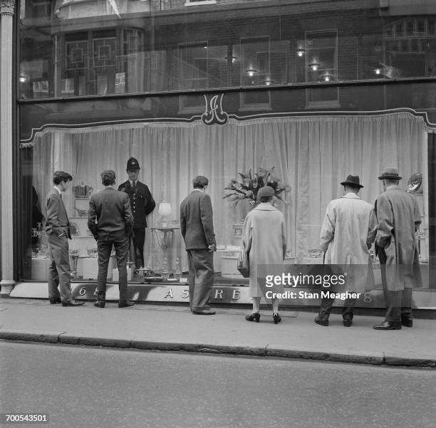 Dummy policeman in the window of Asprey's, a jeweller's in London's Bond Street, 'guarding' a £30,000 gold plate, 15th November 1960.