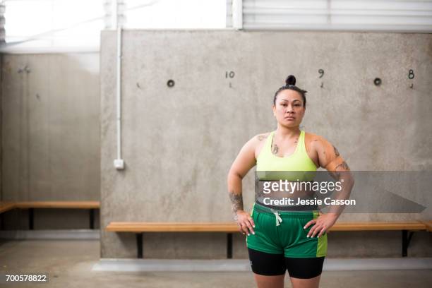 Portrait of female rugby player in sports bra and shorts standing in changing rooms looking into lens