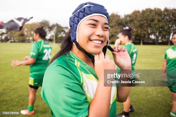 female rugby player is smiling and putting on head gear - rugby league stockfoto's en -beelden