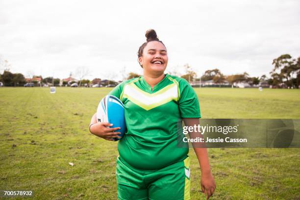 portrait of female rugby player laughing with ball outside on rugby field - rugby portraits stock-fotos und bilder