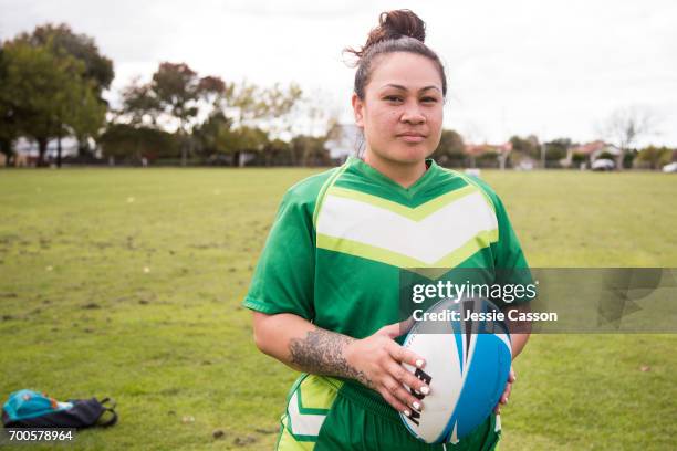 portrait of female rugby player with ball looking into lens outside on rugby field - grittywomantrend stock pictures, royalty-free photos & images