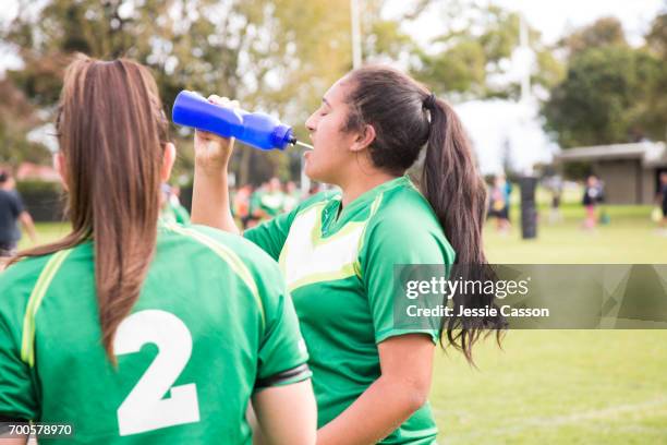 female rugby players drink water and cool off at side of pitch - grittywomantrend stock pictures, royalty-free photos & images