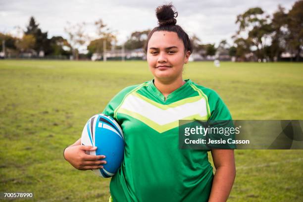 Portrait of female rugby player smiling with ball outside on rugby field