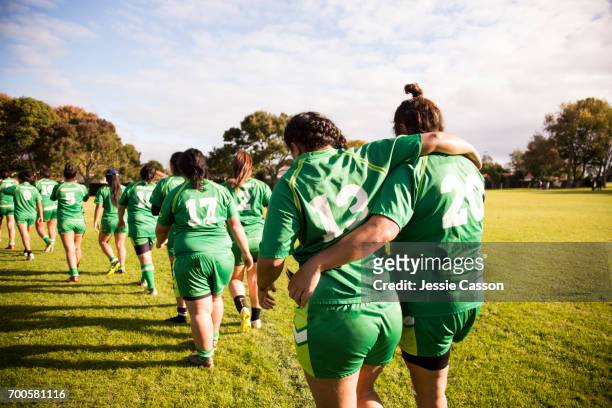 line of female rugby players walking away from camera, one player is helping an injured player - rugby competition stockfoto's en -beelden