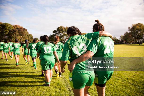 line of female rugby players walking away from camera, one player is helping an injured player - new zealand rugby stock pictures, royalty-free photos & images