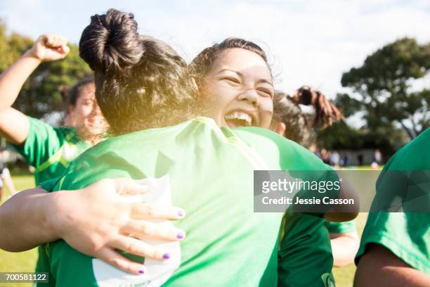 two female sports players have celebratory embrace on field - rugby sport stock pictures, royalty-free photos & images