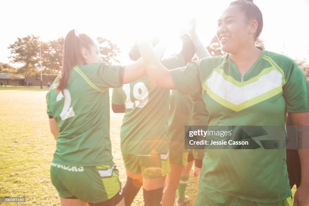 Female rugby players on field celebrating after match