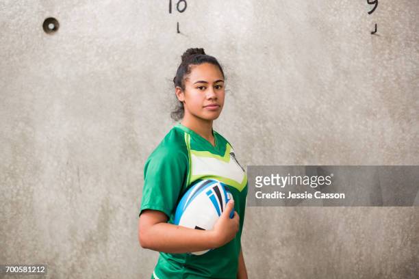 Female rugby player in changing rooms holding ball