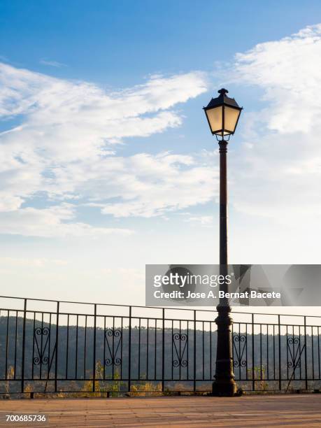 viewing-point on a mountain with a rail of iron and a lamppost, illuminated by the light of the dawn - baranda fotografías e imágenes de stock