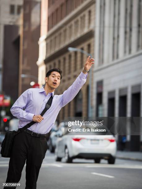 chinese businessman hailing taxi in city - hail stock pictures, royalty-free photos & images