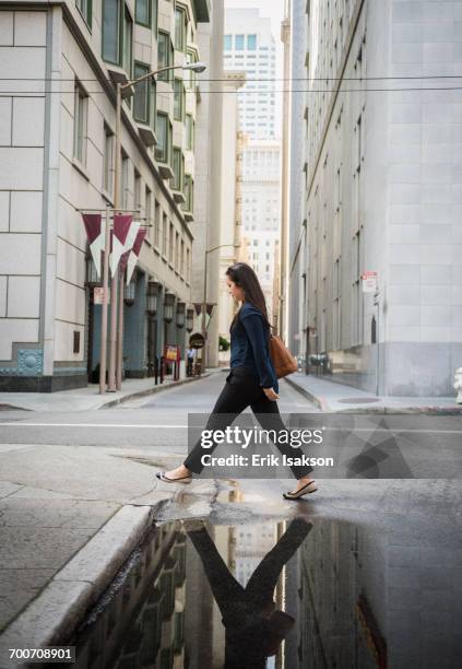 reflection in puddle of chinese businesswoman crossing street - flaque photos et images de collection