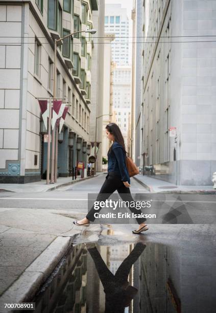 reflection in puddle of chinese businesswoman crossing street - san francisco street stockfoto's en -beelden