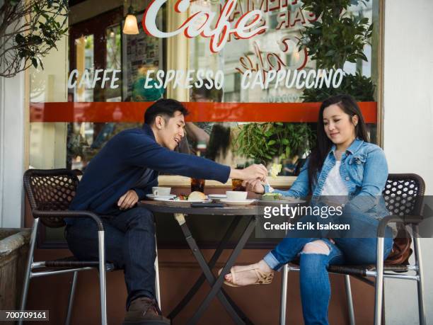chinese man tasting food of woman at outdoor cafe - coppie cibo food bistrot foto e immagini stock