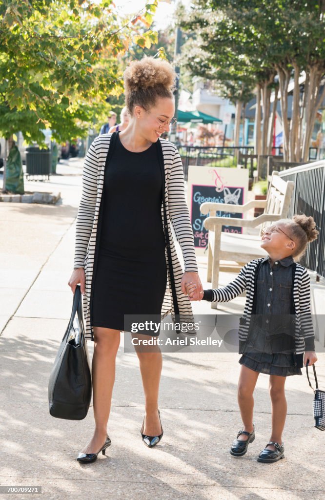 Mother and daughter businesswomen walking on sidewalk