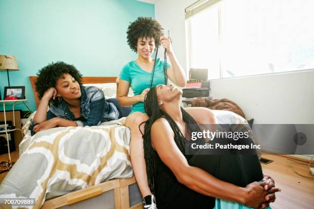 woman braiding hair of friend in bedroom - braided hair photos et images de collection