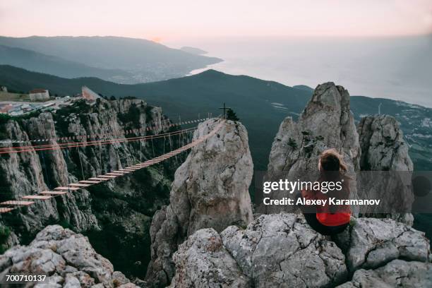 caucasian woman sitting on mountain near footbridge - rope bridge stock pictures, royalty-free photos & images