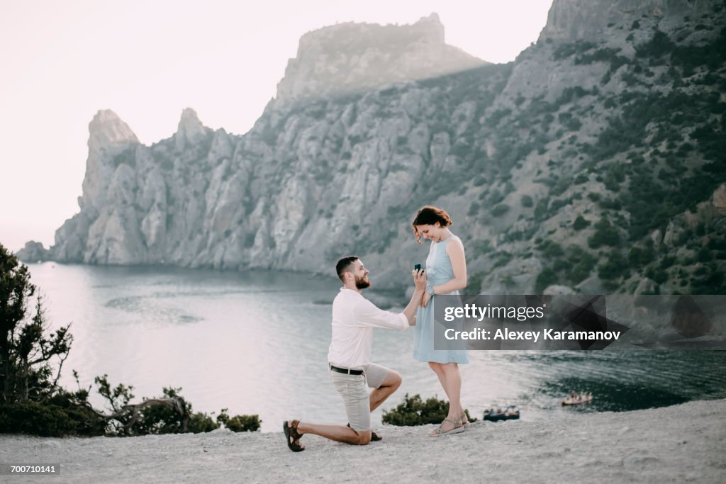 Caucasian man proposing marriage to woman at beach