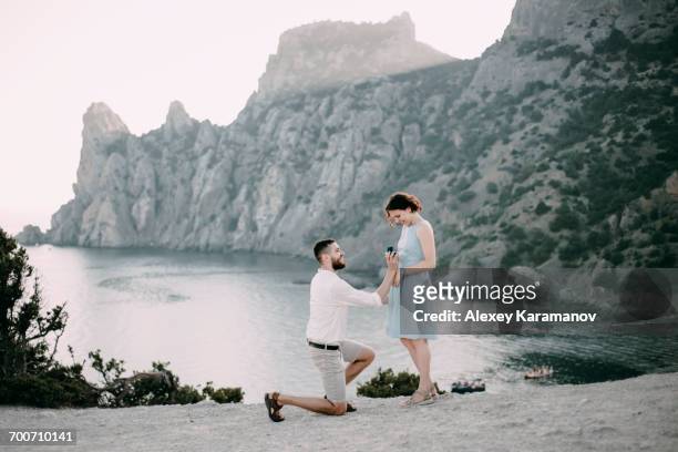 caucasian man proposing marriage to woman at beach - noivo imagens e fotografias de stock