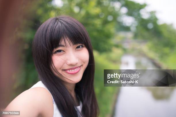 自然の selfie 写真を撮る幸せな若い女 - 若い女性 日本人 顔 ストックフォトと画像