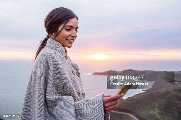 smiling indian woman texting on cell phone near shore - woman holding smart phone stock pictures, royalty-free photos & images