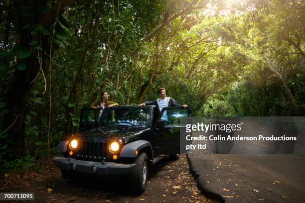 couple standing in car on side of forest road - asian couple car stockfoto's en -beelden