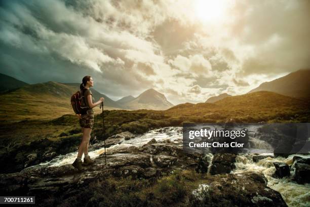 caucasian woman hiking on rocks near river - highlands schottland wandern stock-fotos und bilder