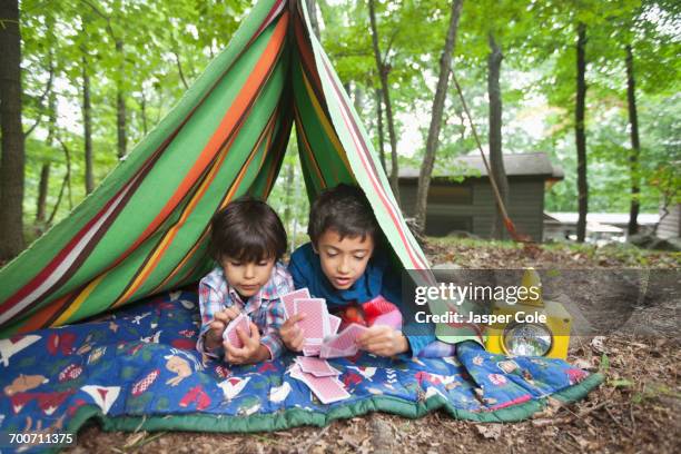 mixed race boys playing card game in blanket fort - camping games stockfoto's en -beelden