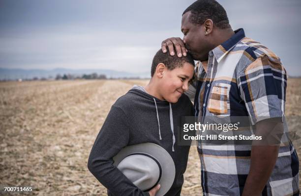 Father kissing son on head in field